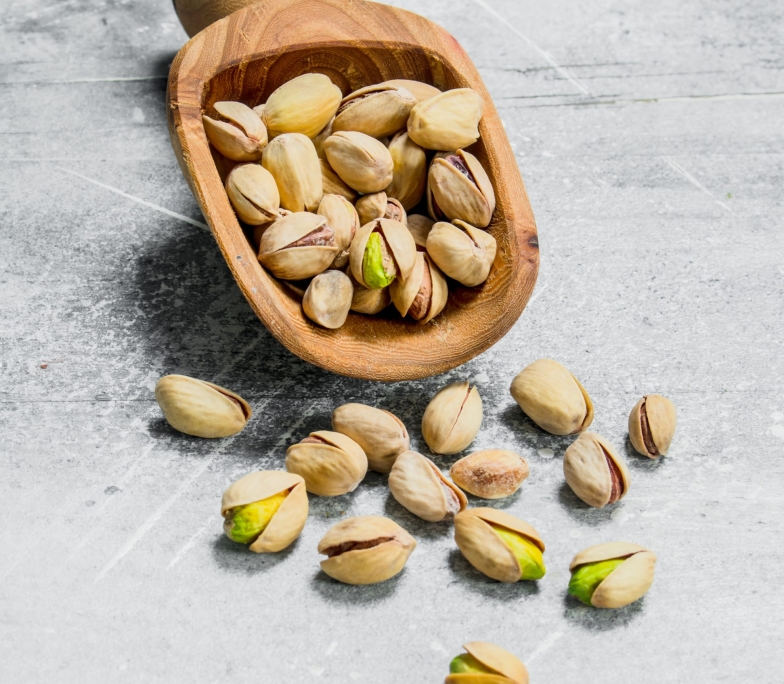 Pistachios in a wooden scoop.